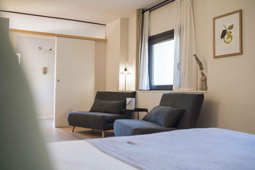 Habitació El Llimoner amb butaques grises, làmpada i làmina d'una llimona