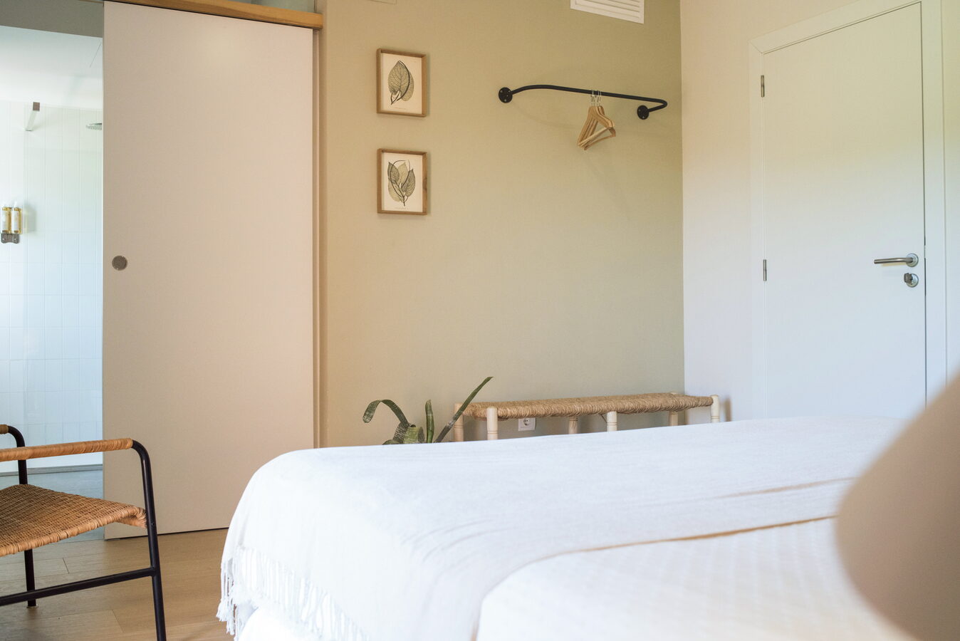 Habitació amb llit blanc, làmina botànica i penjador de paret negre