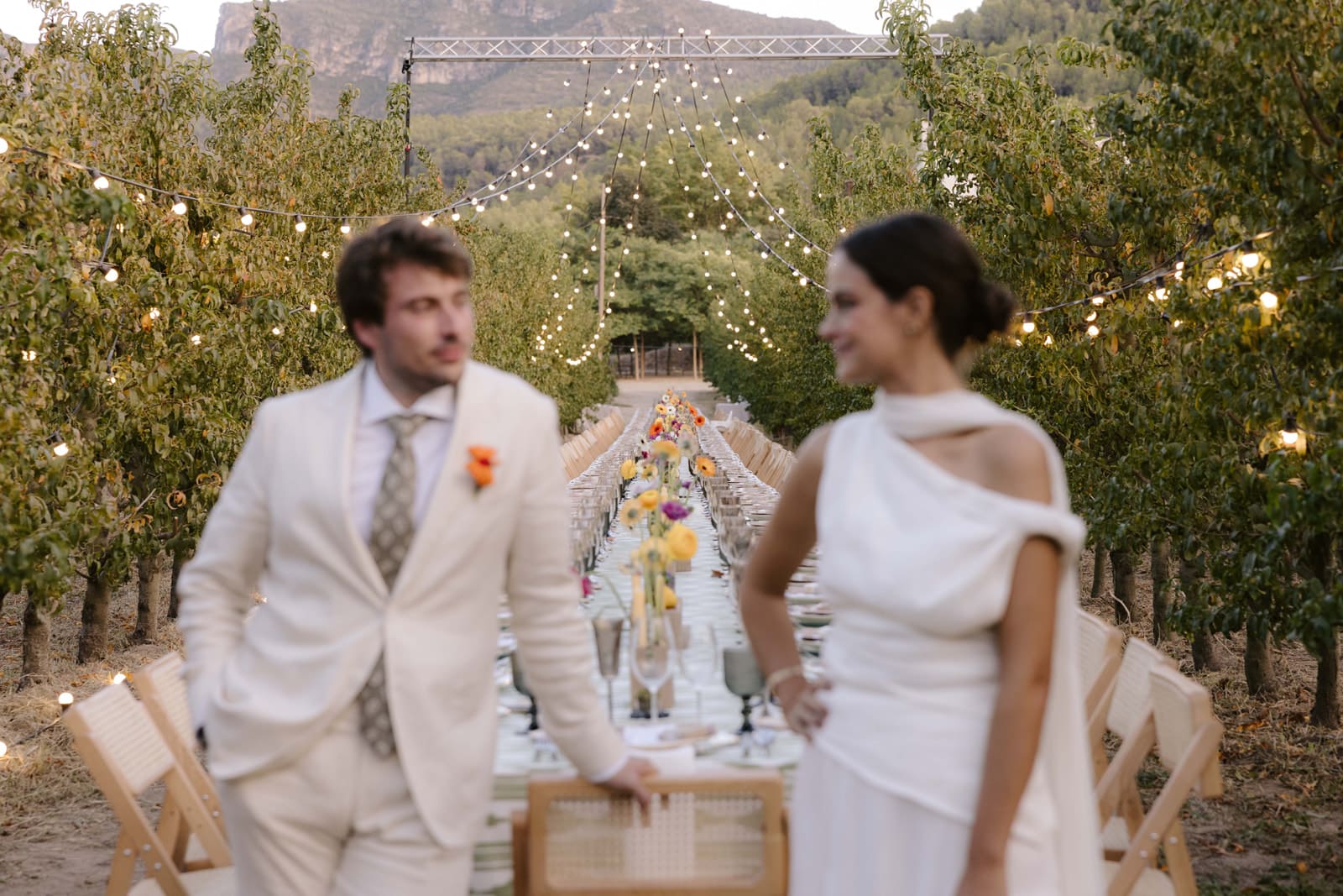 Nuvis passejant entre els arbres davant la taula de banquet amb muntanyes al fons
