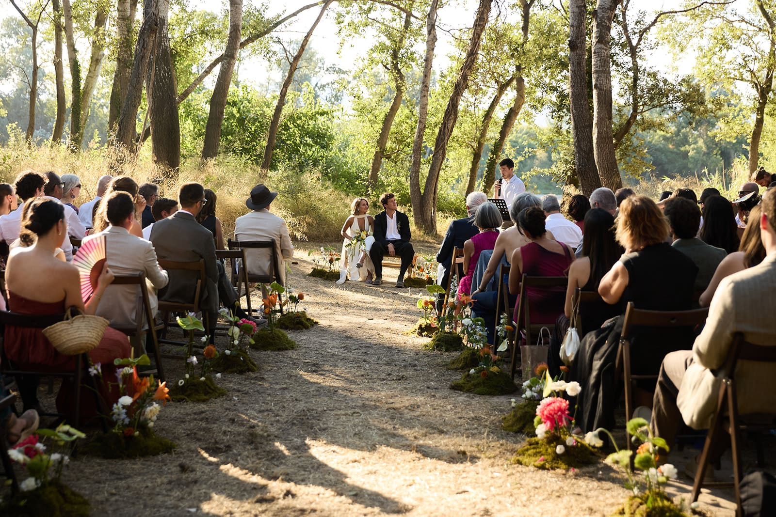 Cerimònia de boda a l'aire lliure entre arbres amb els convidats asseguts