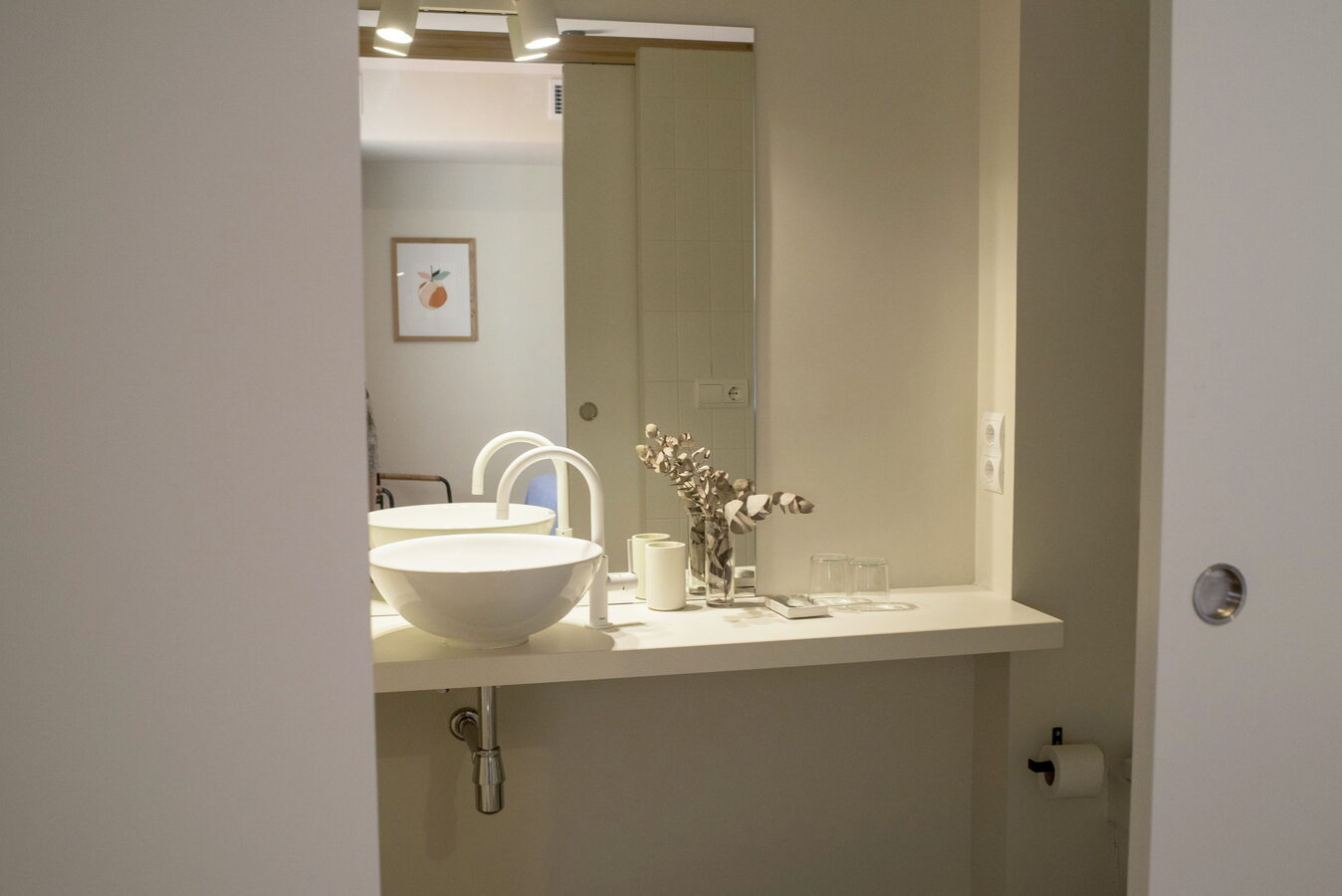 Lavabo amb pica rodona blanca, mirall i estris de bany