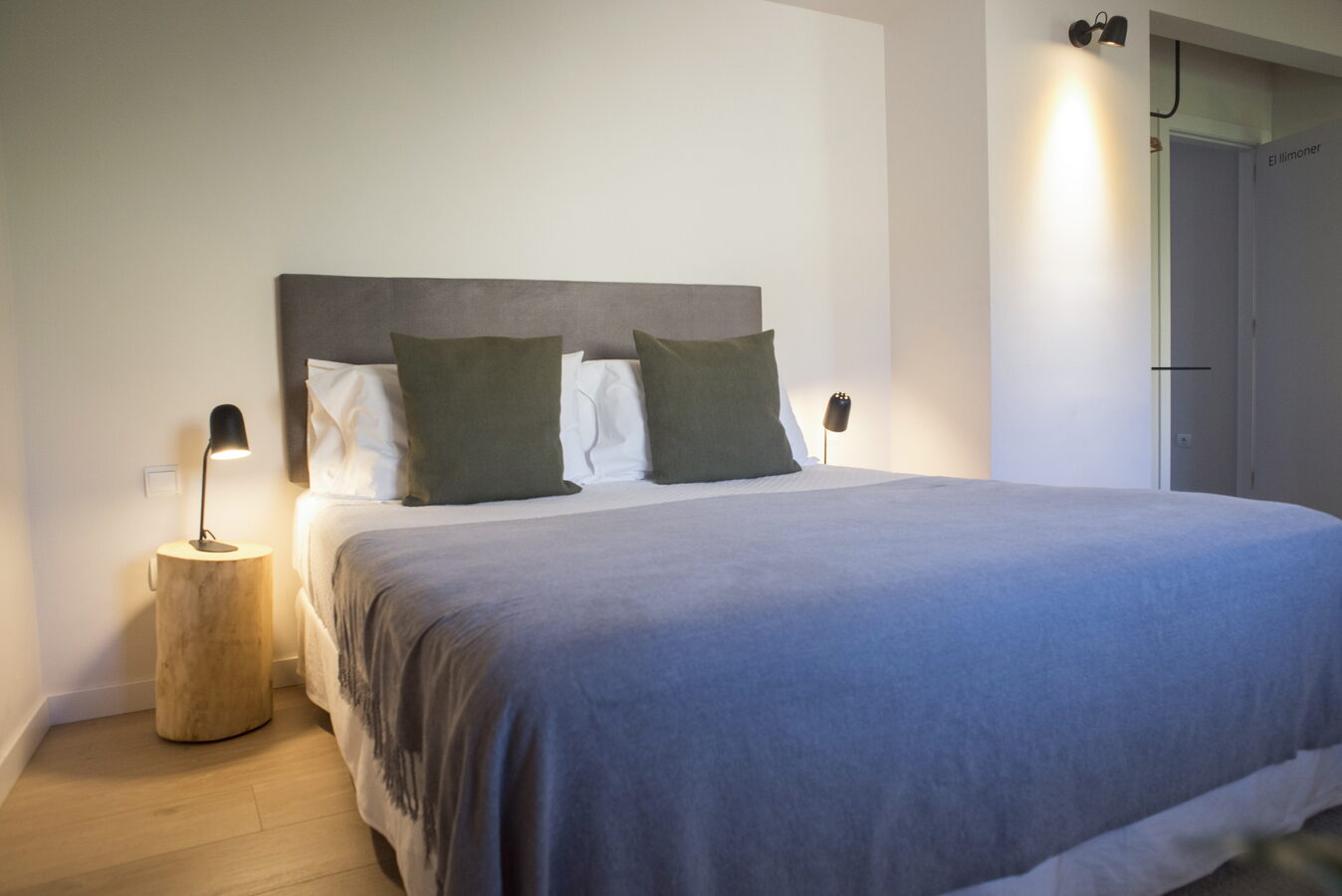 Llit de matrimoni amb coixins verds i tauleta de tronc a l'habitació El Llimoner