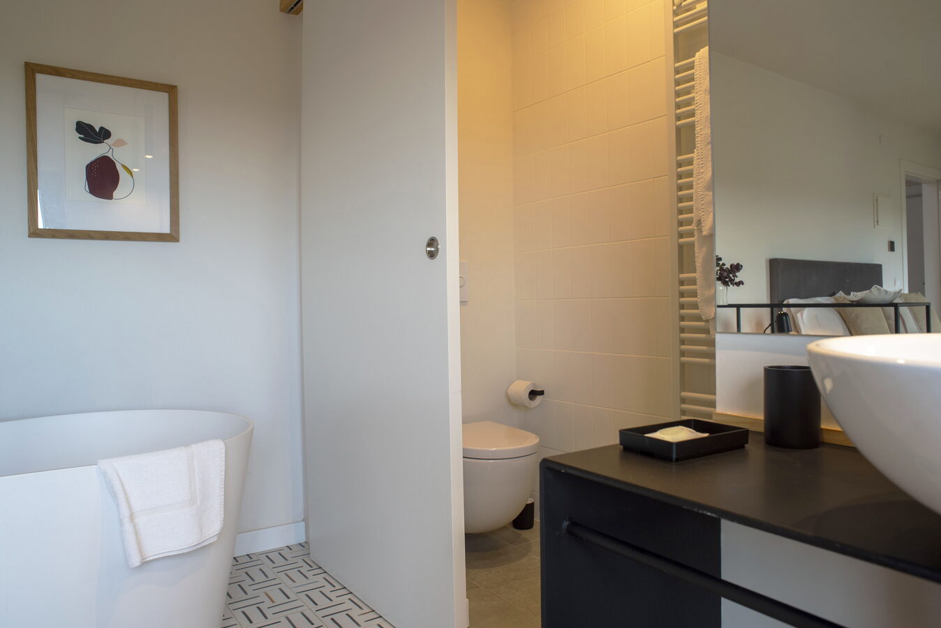 Bany de la habitació amb banyera, vàter suspès i lavabo sobre moble negre