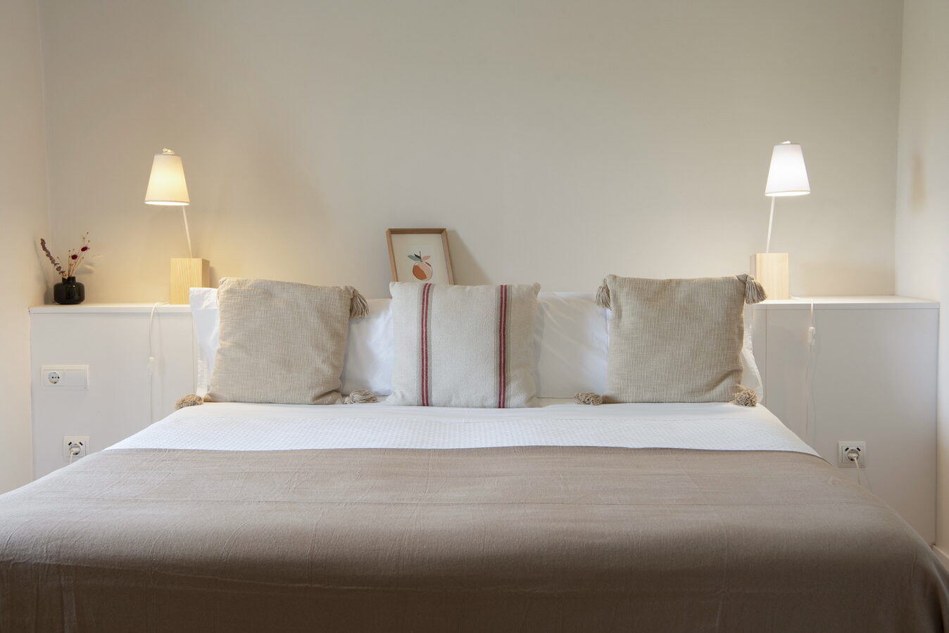 Llit de matrimoni amb coixins de lli i làmpades de nit a la habitació La Prunera