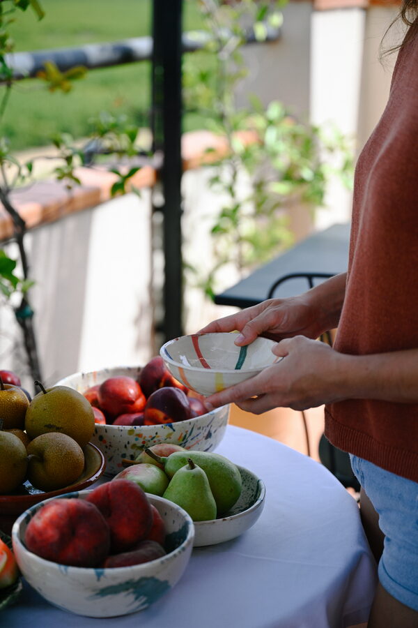 Persona amb un bol al costat de fruita fresca de temporada