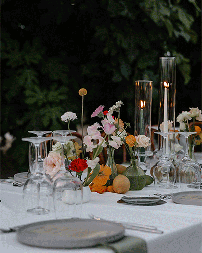 Detall de taula de casament amb flors, espelmes i copes davant la vegetació