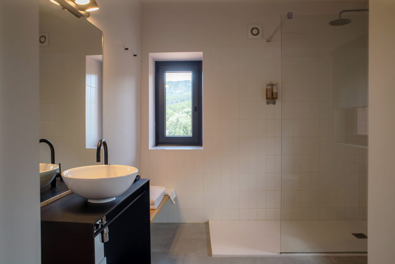 Bany ampli amb doble lavabo, dutxa i finestra amb vistes a la muntanya