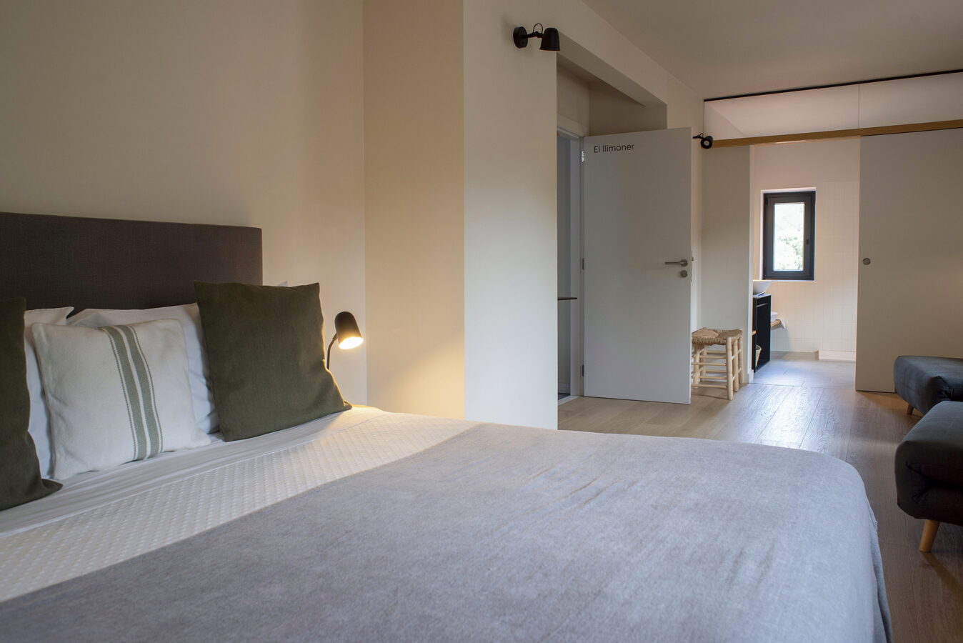 Habitació El Llimoner amb llit de coixins verds i vista cap al bany