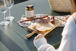 Taula d'aperitiu amb taula de formatge, embotit, olives i copes de vi